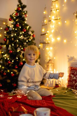 Tatlı çocuk, oğlum, Noel için süslü bir odada sarı bir koltukta oturuyor, rahat bir yer.