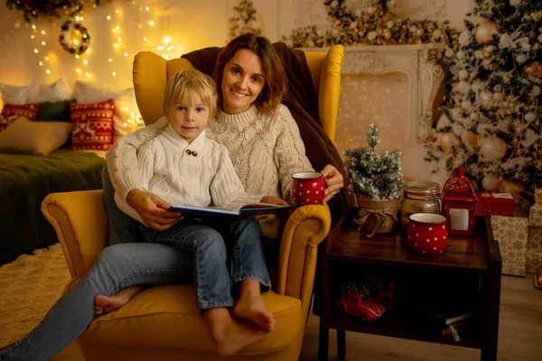 クリスマスの装飾された部屋の黄色のアームチェアに座っている母親と幼児 居心地の良い場所 — ストック写真
