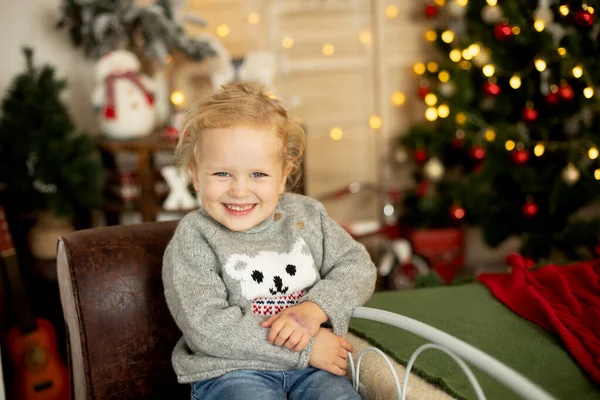 可爱的小毛茸茸的小女孩 穿着冬季圣诞毛衣 坐在舒适的房间里 装饰着圣诞的气氛 — 图库照片