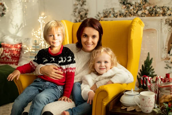 クリスマスのために装飾された居心地の良い部屋に座って 冬のクリスマスのセーターの母と子供 — ストック写真