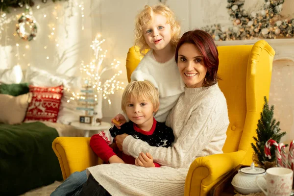 クリスマスのために装飾された居心地の良い部屋に座って 冬のクリスマスのセーターの母と子供 — ストック写真