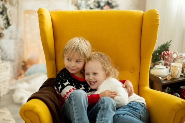 可爱的小毛茸茸的小女孩 穿着冬季圣诞毛衣 坐在舒适的房间里 装饰着圣诞的气氛 图库图片