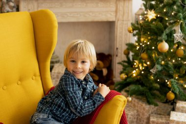 Sevimli çocuk, oğlum, Noel için süslü bir odada oynuyor, rahat bir yerde.