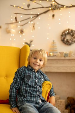 Sevimli çocuk, oğlum, Noel için süslü bir odada oynuyor, rahat bir yerde.