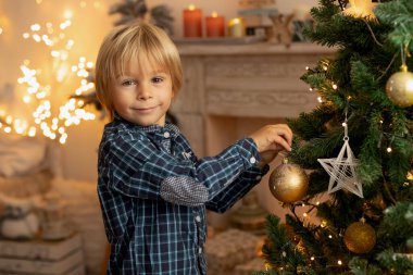 Sevimli çocuk, oğlum, Noel için süslü bir odada oynuyor, rahat bir yerde.