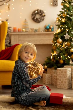 Sevimli çocuk, oğlum, Noel için süslü bir odada oynuyor, rahat bir yerde.