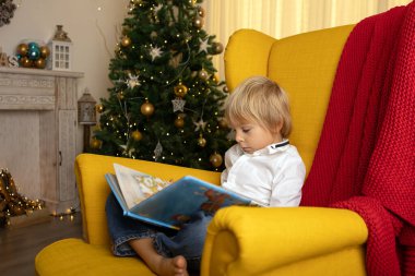 Sevimli çocuk, oğlum, Noel için süslü bir odada oynuyor, rahat bir yerde.