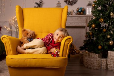 Sevimli çocuk, oğlum, Noel için süslü bir odada oynuyor, rahat bir yerde.
