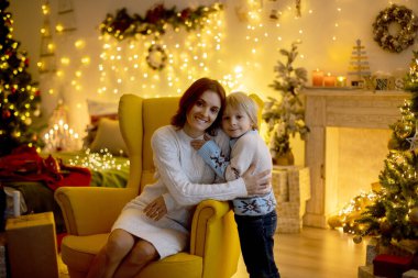 Tatlı çocuk, oğlum, Noel için süslü bir odada sarı bir koltukta oturuyor, rahat bir yer.