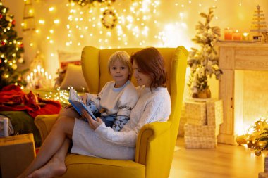 Tatlı çocuk, oğlum, Noel için süslü bir odada sarı bir koltukta oturuyor, rahat bir yer.