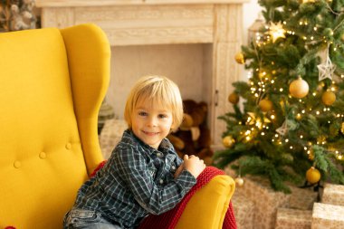 Sevimli çocuk, oğlum, Noel için süslü bir odada oynuyor, rahat bir yerde.