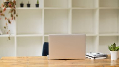 Konforlu ofis odası, dizüstü bilgisayar ve ahşap masa malzemeleri.