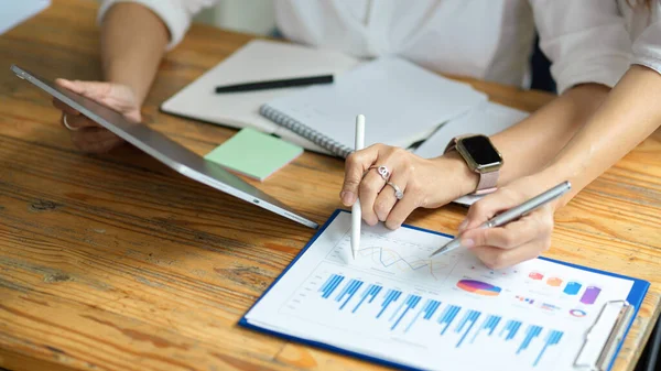 Üst düzey yönetici kadın akıl hocasının yeni finans asistanına ders verirken, tablet ve finansal veriler üzerinde çalışırken, 