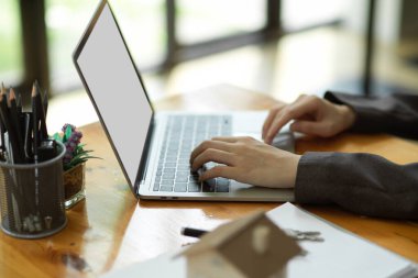 Dizüstü bilgisayarda çalışan, dizüstü bilgisayarında kira sözleşmesi yazan bir kadın emlakçının yan görüntüsü. dizüstü bilgisayar boş ekran modeli.