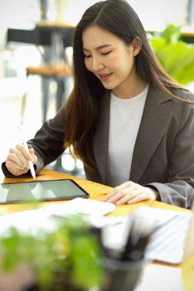 Portrait of asian businesswoman consultant working in her modern office, working on portable tablet computer.
