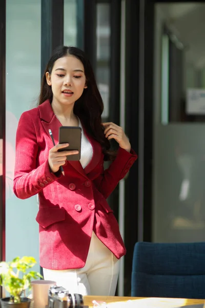 Elegance millennial business entrepreneur in the office, using modern smartphone to checking her online store