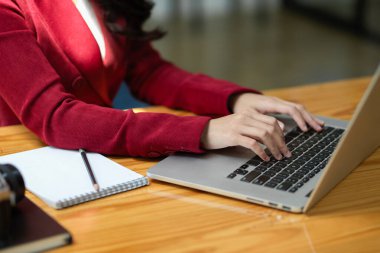 Zarif genç bir iş kadını dizüstü bilgisayarında çalışıyor, klavyeyle yazı yazıyor ve iş e-postası gönderiyor. Kesilen resim