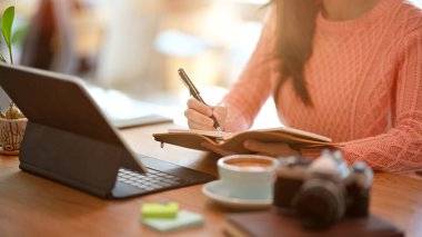 Kesilmiş görüntü Genç serbest çalışan blog yazarı günlüğüne notlar yazan, restoranda oturan.