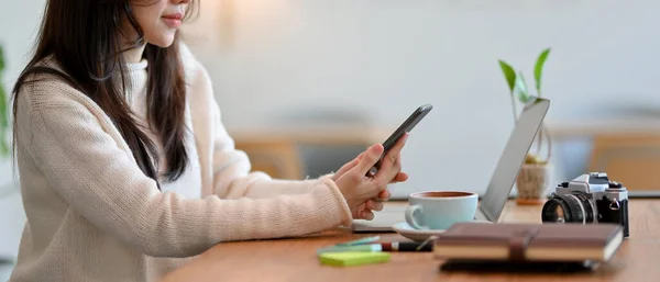 サイドビュー クローズアップ 女性フリーランスは自宅のオフィスに座りながら モダンなスマートフォンを使用しています — ストック写真