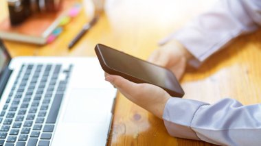 İş kadınının el ele tutuşurken çekilmiş görüntüsü, modern akıllı telefonu kullanılıyor..