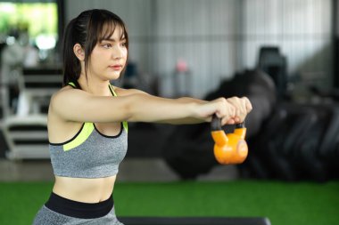 Ağırlık antrenmanı, CrossFit egzersizi, vücut geliştirme. Güçlü kadın spor salonunda iki eliyle su ısıtıcısını kaldırıyor..