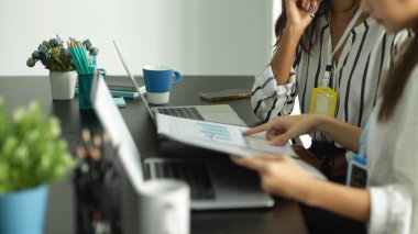 Ofiste çalışan iş kadınlarının mali iş bütçesi planlama belgeleriyle birlikte çalışmalarının kırpılmış görüntüsü..