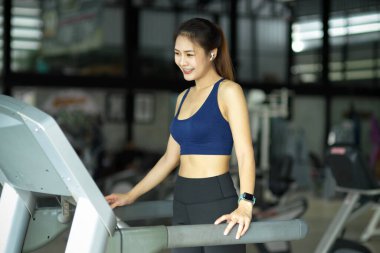 Zayıf formda fitness kızı spor kulübünde koşu bandında egzersiz yapıyor, egzersiz makinesinde koşuyor..