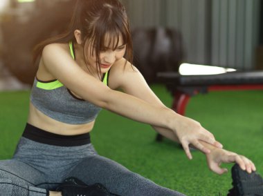 Çekici, formda bir kadın antrenmandan sonra sakinleşir, spor salonunda bacağını esneterek egzersiz yapar..