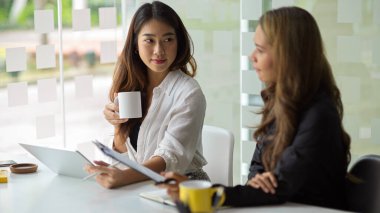 Genç bir Asyalı iş kadını, iş arkadaşlarından birinin bir pazarlama projesinin bileşenini....