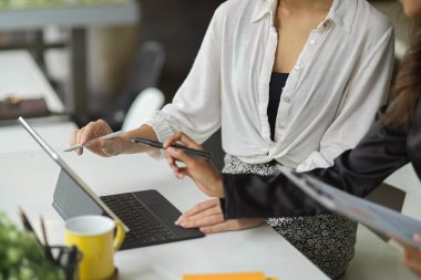 Modern açık uzay ofisinde dijital tablet bilgisayarla çalışan iki iş kadını.