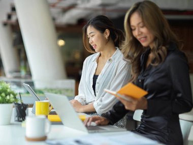 Milenyum çalışanları modern ofiste oturup, görevlerini dizüstü bilgisayarla yapıyorlar.. 