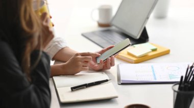 İnternet sitesindeki ilginç içeriği ofisteki bir arkadaşa göstermek için akıllı telefonunu kullanan bir bayan meslektaşın yakın plan fotoğrafı..