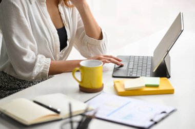 Ödevini yapmak için modern bir tablet bilgisayar kullanan bir iş kadınının kırpılmış, yakın plan fotoğrafı..