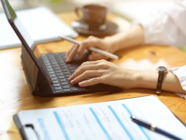 Hastane ofisinde dijital tablet bilgisayarı üzerinde çalışan kadın doktorun kesilmiş görüntüsü..