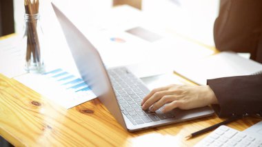 Meşgul bir iş kadınının kesilmiş resmi finansal veri raporunu analiz eder, dizüstü bilgisayarla çalışır..