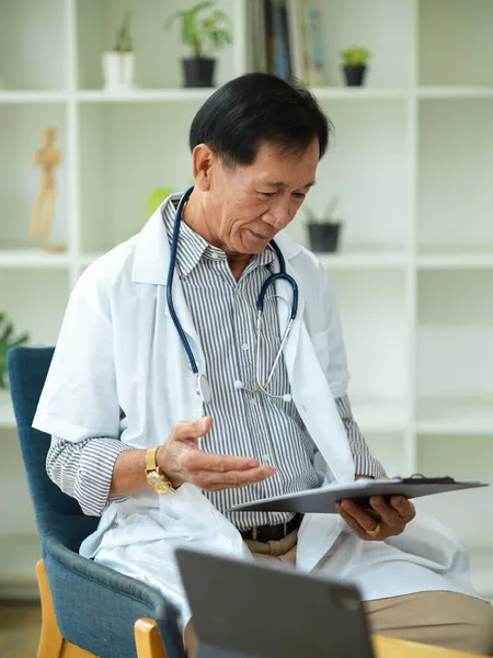 一位中年专科医生在医疗剪贴板上检查并阅读了一位受伤病人的治疗计划 — 图库照片