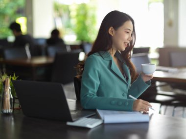 Başarılı kadın patronun şık bir takım elbiseyle kahvecide oturup sabah kahvesini içişi. uzak çalışma konsepti.