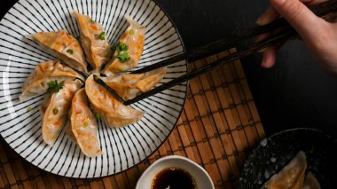 Üst manzara, yakın plan bir kadının elleri buharlı Japon gyoza hamur köftesi ile yemek çubukları kullanır. Asya mutfağı. 