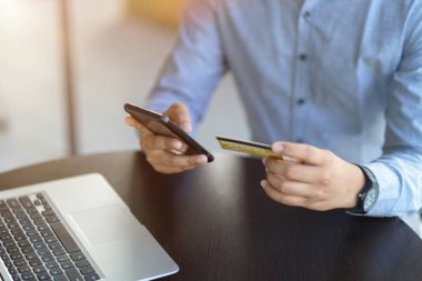 Akıllı telefon ve kredi kartı tutan bir adam. Çevrimiçi bankacılık, online ödeme, internet para transferi, para transferi. kırpılmış resim
