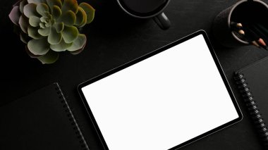 Modern karanlık çalışma masasında beyaz ekran modeli ve aksesuarları olan taşınabilir tablet bilgisayar. en üstteki görünüm