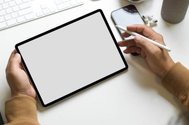 Yakın plan, çalışma alanında modern dijital tablet bilgisayarı üzerinde çalışan serbest çalışan bir erkek. tablet boş ekran modellemesi.