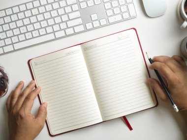 Günlükteki boş sayfalar, modern çalışma tablosu. Elinde kitap olan bir adamın elleri. öğrenim kavramı