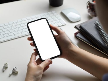 Modern beyaz ofis çalışma masasında elinde boş ekran akıllı telefon tutan iş kadını ya da kadın..