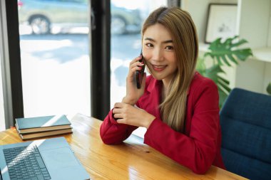 Kendine güvenen Asyalı genç iş kadınları ya da ofisteki müşterisiyle telefonda konuşan bayan girişimci. iş telefonu arama kavramı.