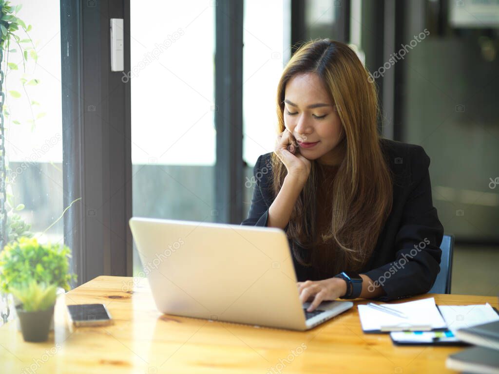 Attractive asian young business woman using laptop computer at her workspace. Female assistant working on laptop computer.