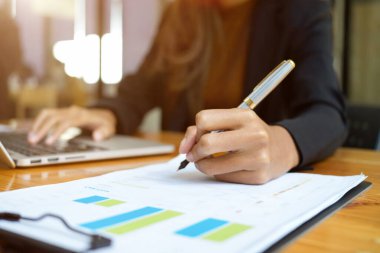 Yakın plan kadın eli, masadaki mali rapor evraklarına bir şeyler yazıyor. iş insanları konsepti.