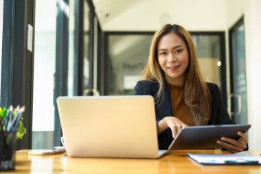 Masasında çalışan kadın bir iş adamı, dizüstü bilgisayarının önünde oturuyor..
