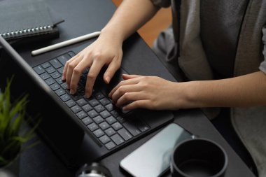 Modern ofis masasındaki tablet dokunmatik klavyeye yazı yazan bir iş kadınının kırpılmış görüntüsü..