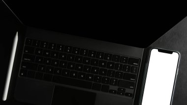 Yakın plan, modern siyah tabletin ya da masadaki akıllı telefon boş ekranlı dokunmatik bilgisayarın üst görünümü.