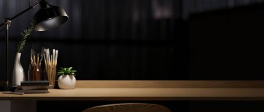 Resim aletleri, kitaplar, dekor, masa lambası ve ahşap masa üzerindeki fotokopi alanı ile modern karanlık çalışma alanı. 3d görüntüleme, 3d illüstrasyon